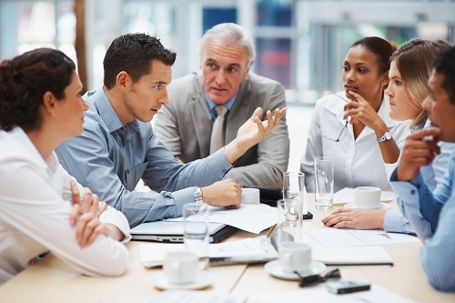 group of business professionals sitting around a table talking